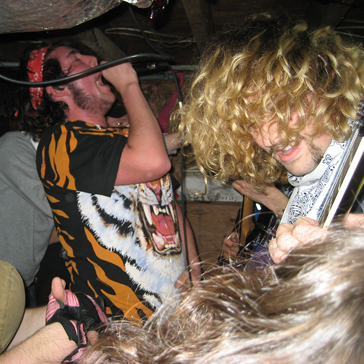 A chaotic scene of a band playing a punk concert in a basement.
