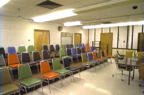 An eerie room full of multi-colored plastic chairs set up on risers like a stage.