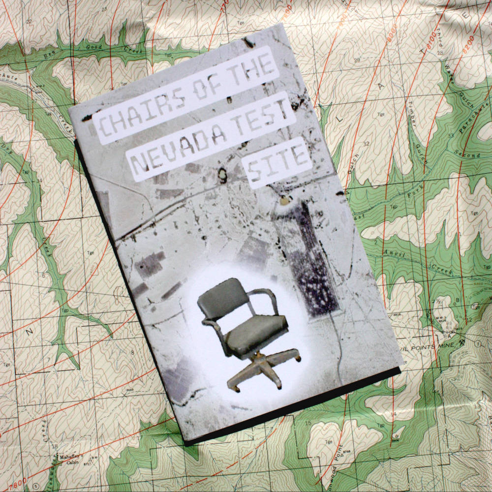 A zine entitled Chairs of the Nevada Test Site, displayed on top of a topographic geologic map.